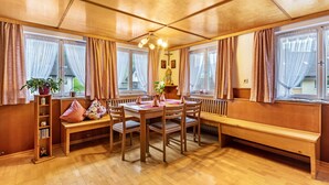 A wooden interior with a dining table, benches, and a radiator.