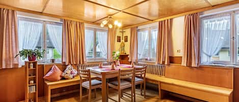 A wooden interior with a dining table, benches, and a radiator.