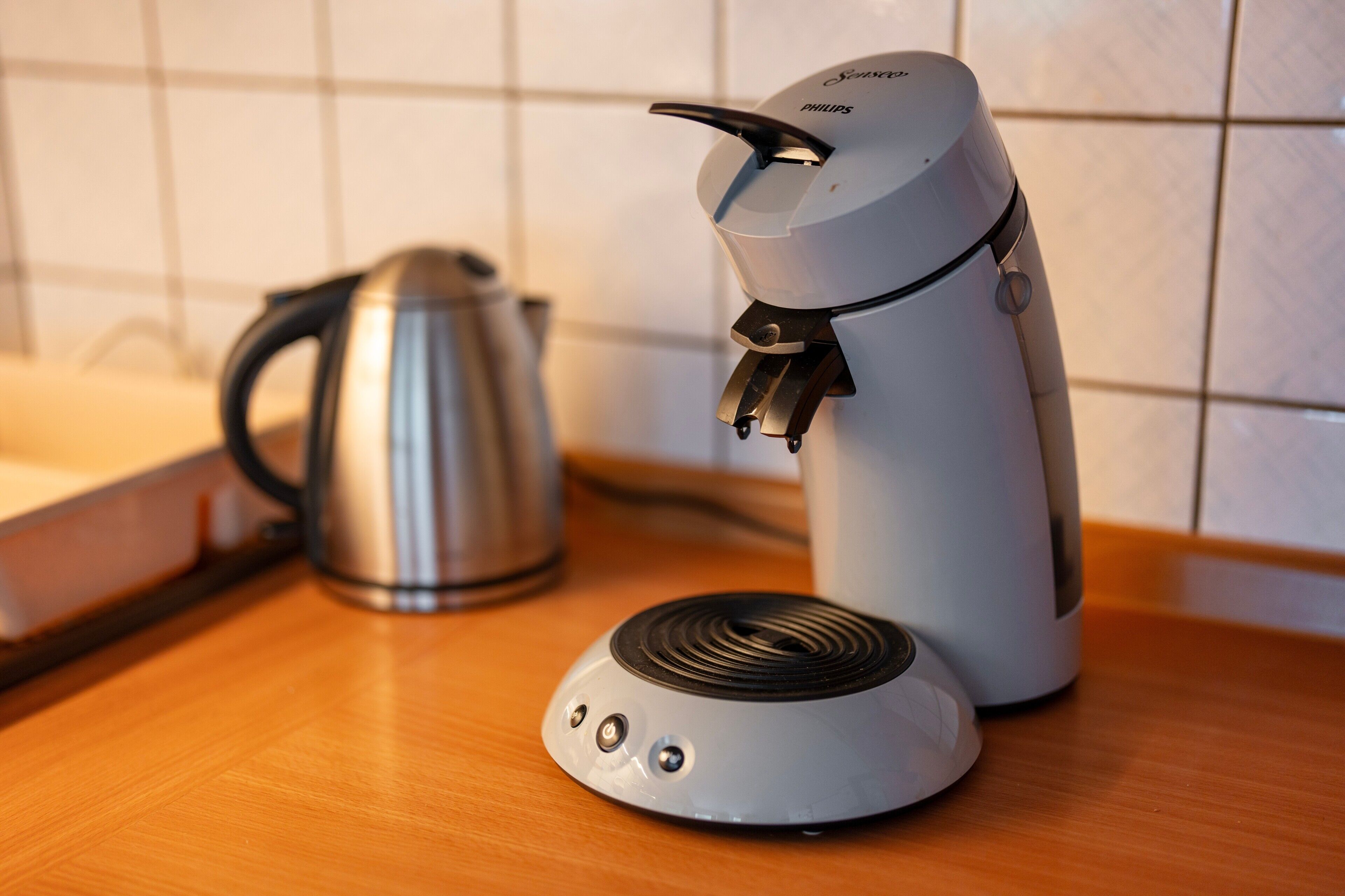 Une machine à café et une bouilloire sur un plan de travail en bois.