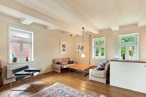 A room with a sofa, a coffee table, a hanging light fixture, and a radiator.