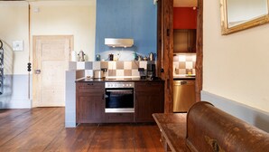Une cuisine avec des meubles de rangement en bois, un four encastré, une machine à café et un lave-vaisselle.