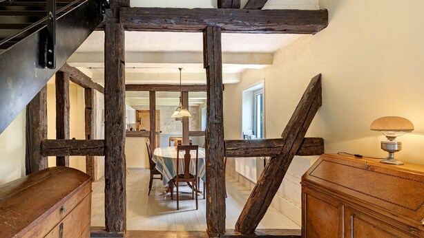 A rustic interior with exposed wooden beams, a dining area with a table and chairs, and a wooden cabinet. - Apartment 'Altes Pfarrhaus - Durchblick' with Private Garden and Wi-Fi (Hüttenrode)