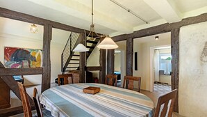 A dining area with a striped tablecloth, wooden chairs, a chandelier, and exposed wooden beams. - Apartment 'Altes Pfarrhaus - Durchblick' with Private Garden and Wi-Fi (Hüttenrode)