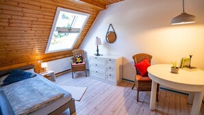 Una habitación acogedora con una cama, una silla, una mesa y un ventanal.