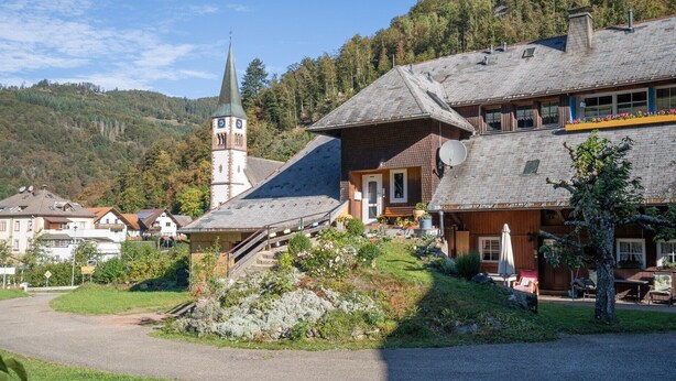 Un pueblo europeo tradicional con una torre de iglesia, casas de madera y un camino de grava.