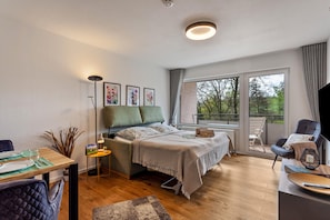 Una camera da letto moderna con un letto, un comodino, una lampada e vista sull'esterno attraverso una grande finestra.