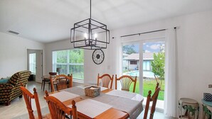A dining area with a wooden table, chairs, and a hanging light fixture. - Relaxing coastal home centrally located in Port Charlotte - Fireside Cottage (Port Charlotte)