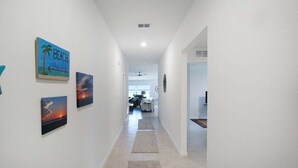 A hallway with artwork on the walls, a ceiling fan, and a view into a dining area. - Relaxing coastal home centrally located in Port Charlotte - Fireside Cottage (Port Charlotte)