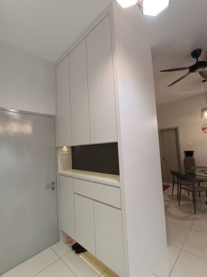 A modern kitchen with white cabinetry, a built-in oven, and a dining area with a table and chairs. - The Horizon Ipoh 18 Amazes (Ipoh)