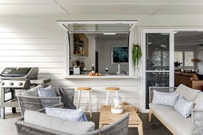 A modern outdoor seating area with wicker furniture, a wooden table, and a grill.