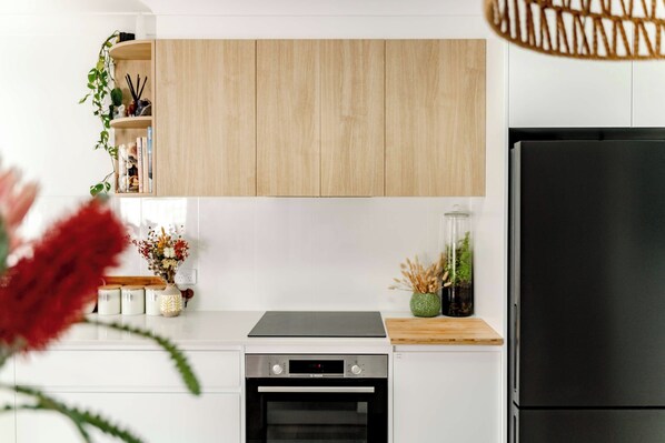 A modern kitchen with white cabinets, a black stove, and a black refrigerator. - 34° Degrees South Culburra - 4 min walk to beach (Culburra Beach)