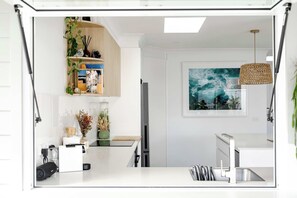 A modern kitchen with white cabinetry, a built-in refrigerator, a sink, and a hanging light fixture. - 34° Degrees South Culburra - 4 min walk to beach (Culburra Beach)