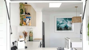 A modern kitchen with white cabinetry, a built-in refrigerator, a sink, and a hanging light fixture.