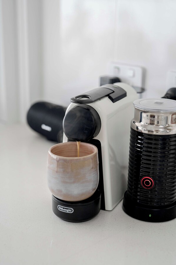 A coffee machine, a cup, and a lighter on a countertop.
