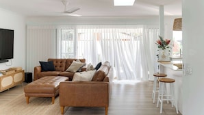 A modern living room with a sectional sofa, ottoman, and bar stools.