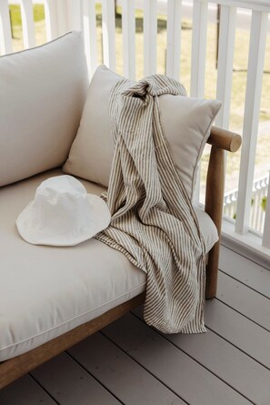 Ein weißes Sofa mit einer gestreiften Decke und einem weißen Hut darauf.