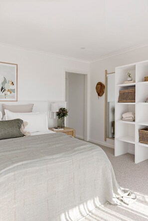 Ein Schlafzimmer mit Bett, Nachttisch, Lampe und einem Kleiderschrank mit Körben.