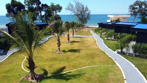 A well-maintained lawn with a winding path, palm trees, and a view of the sea.
