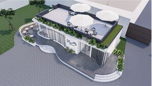 A modern building with a rooftop patio area featuring outdoor seating and umbrellas.