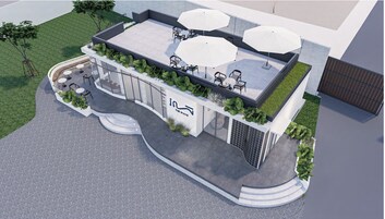Um edifício moderno com um terraço no telhado, com área de estar ao ar livre e guarda-sóis.