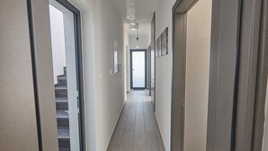 Ein Flur mit Treppe links, einer Tür rechts und einer Leuchte darüber.
