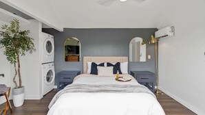 A bedroom with a bed, a washing machine, a dresser, a mirror, and a ceiling fan. - New Tiny Home W/Mountain Views (Weaverville)