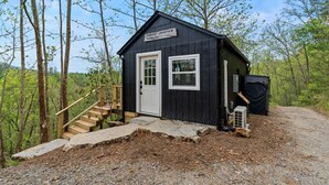 A small cabin with a white door and windows, surrounded by trees, and a sign reading "Harris Mountain Mansion". - New Tiny Home W/Mountain Views (Weaverville)