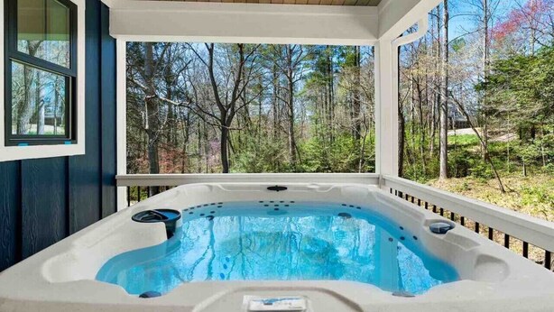 Een hottub op een overdekt terras met uitzicht op een bos.