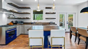 Een moderne keuken met een centraal eiland, inbouwapparatuur en hanglampen.