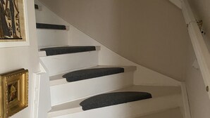 Una escalera con paredes blancas y escalones oscuros.