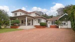 A two-story house with a brick driveway, a covered porch, and a well-maintained garden. - Isoyi on the Mill (Durban North)