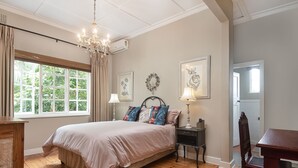 A bedroom with a large bed, a chandelier, a nightstand, and a wooden dresser. - Isoyi on the Mill (Durban North)