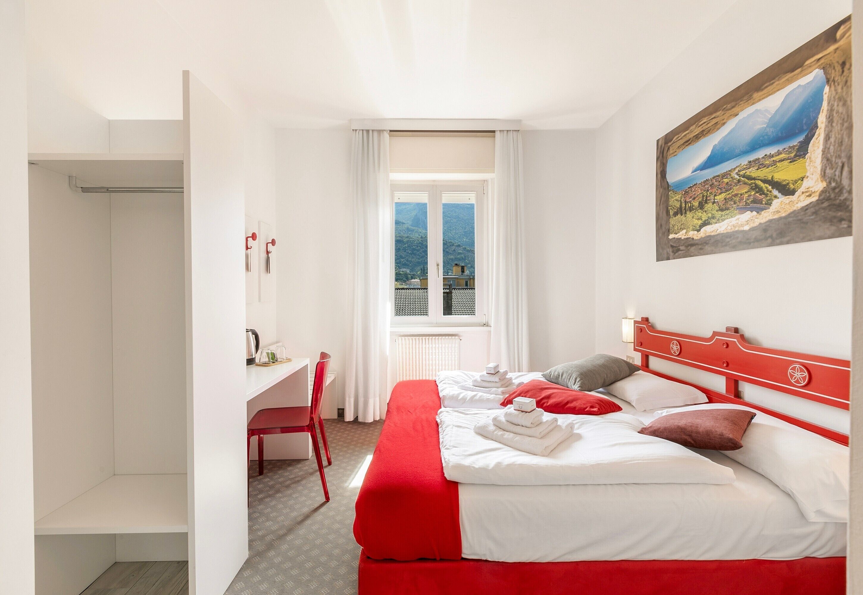 A hotel room with a large bed, a desk, and a window with a view of a mountain and lake.