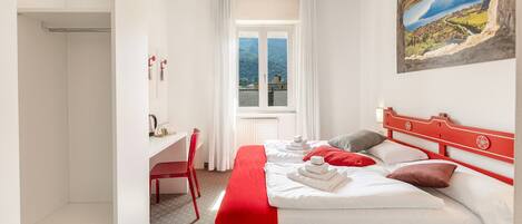 A hotel room with a large bed, a desk, and a window with a view of a mountain and lake.