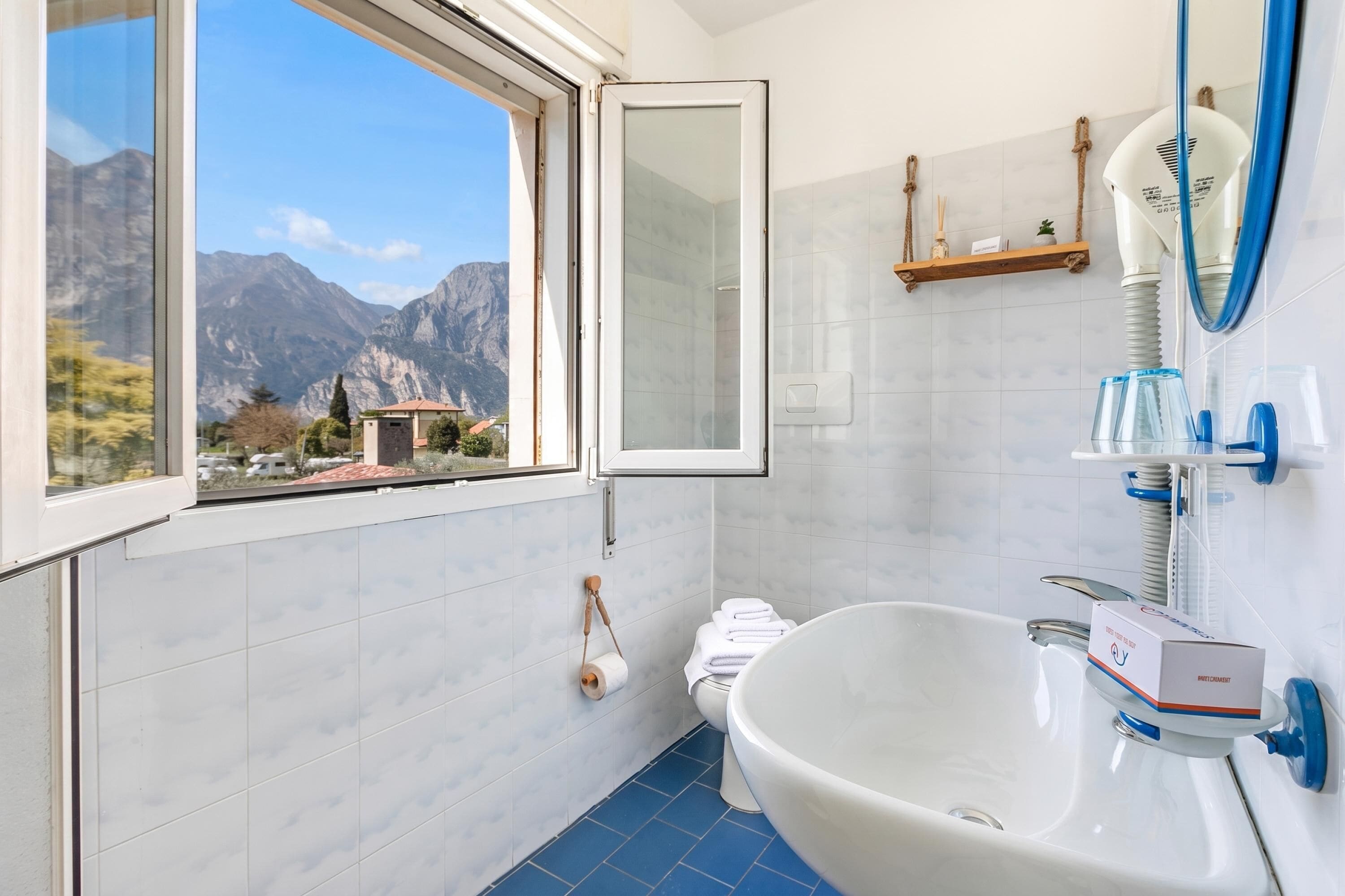 A bathroom with a large window, a sink, a toilet, and a mirror.