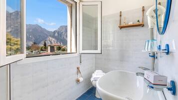 A bathroom with a large window, a sink, a toilet, and a mirror.
