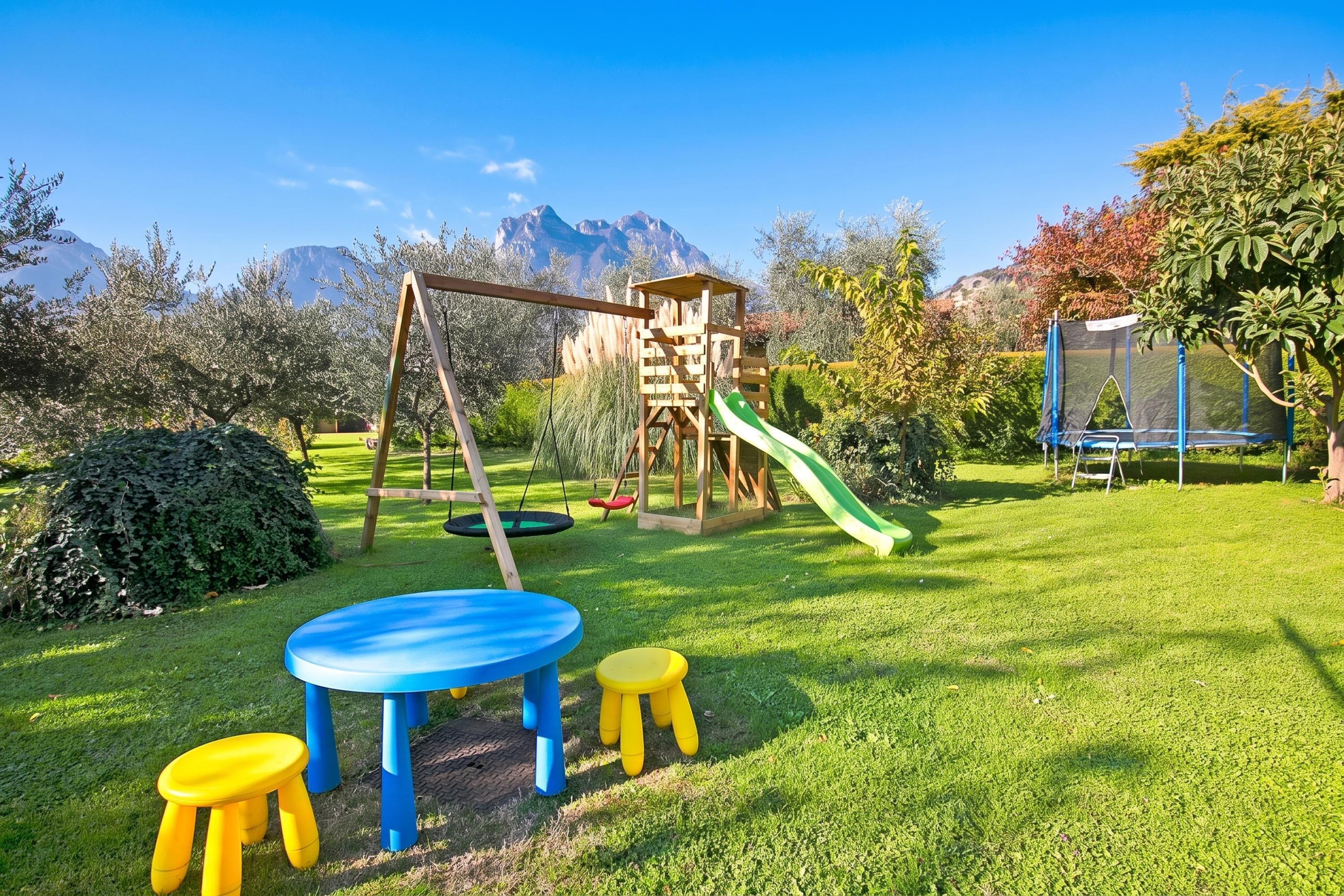 Un'area giochi con altalene, scivolo e struttura per arrampicarsi, immersa nel verde tra l'erba e gli alberi.