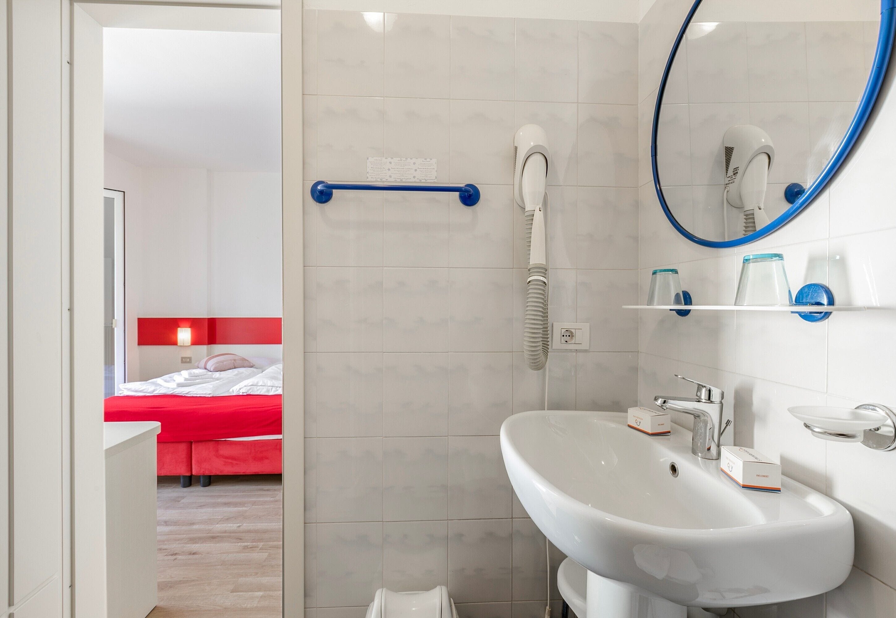 Une salle de bain moderne avec un lavabo blanc, un miroir et un sèche-cheveux.