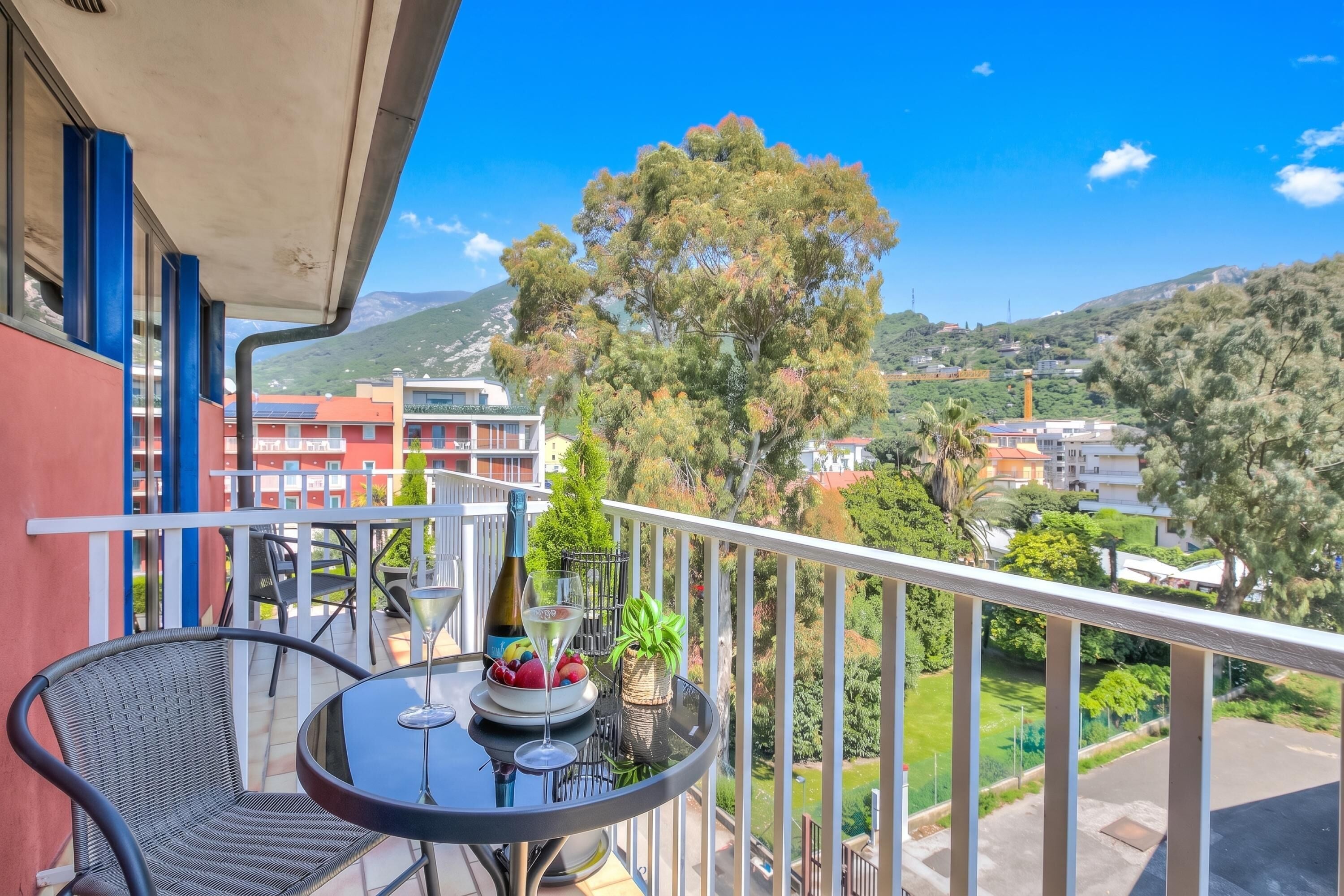 A balcony with a table, chairs, and a bottle of wine.