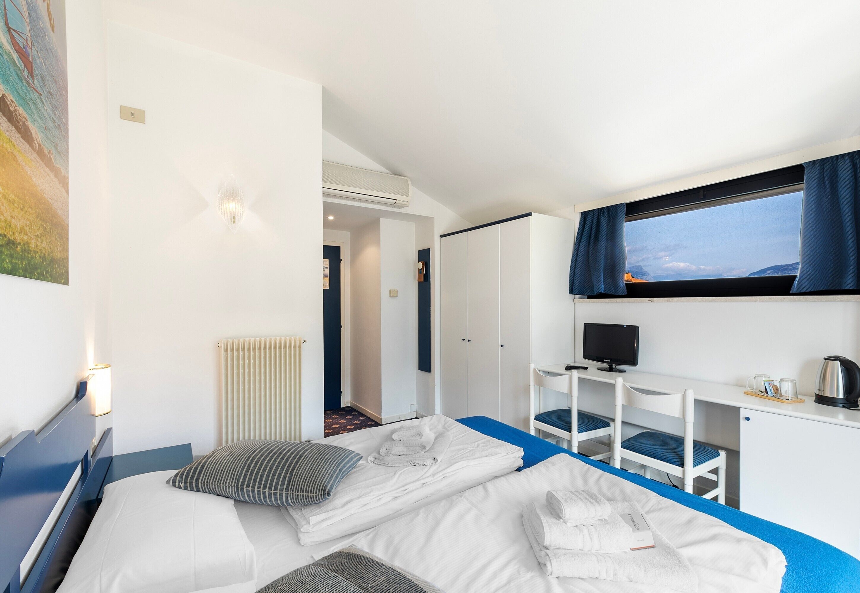 Une chambre d’hôtel équipée d’un lit, d’un bureau, d’une chaise, d’une télévision et d’une fenêtre avec des rideaux.