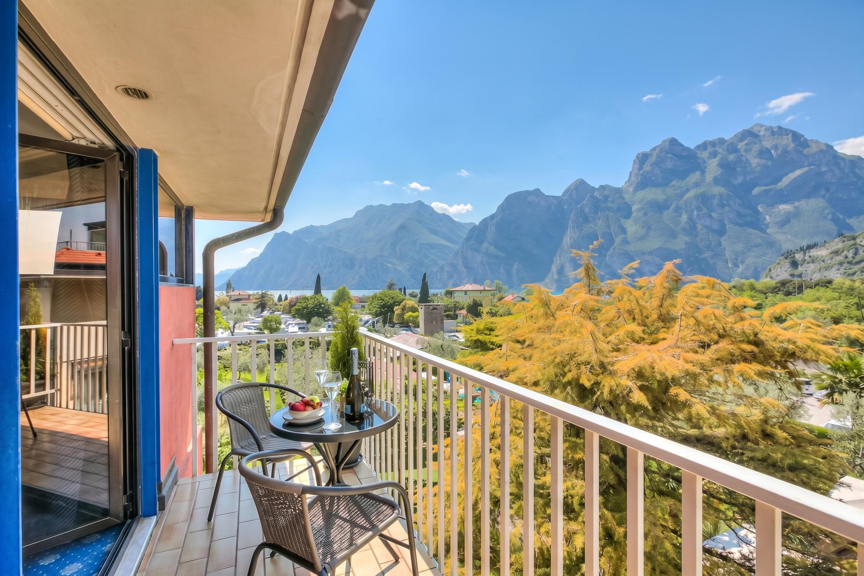 A balcony with a table, chairs, and a bottle of wine.
