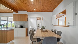 Una cocina moderna con armarios de madera, encimera de mármol y comedor con mesa y sillas de madera.