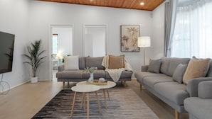 Una sala de estar moderna con un sofá gris, una mesa de centro, un televisor y una planta en maceta.