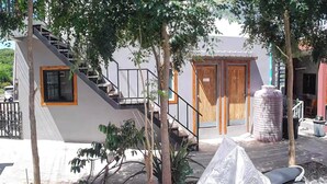 A modern building with a staircase, wooden doors, and a covered outdoor seating area. - Samanta By The Hill (Koh Lan)