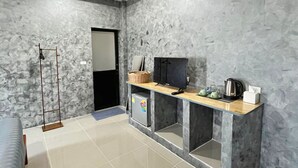 A modern kitchen with a marble backsplash, a built-in fridge, a wooden countertop, and a television. - Samanta By The Hill (Koh Lan)
