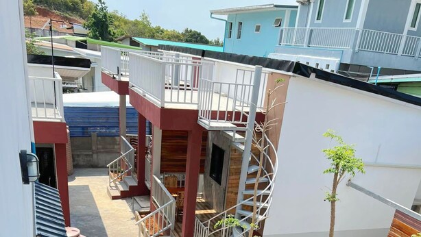 A multi-level residential building with a staircase, outdoor seating area, and a small tree. - Samanta By The Hill (Koh Lan)