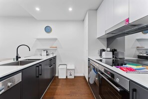 A modern kitchen with a built-in oven, a sink, and a coffee machine.