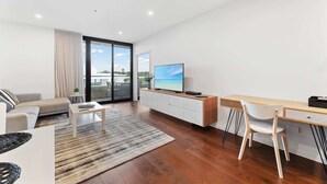 Un salon moderne comprenant un canapé, une table basse, un téléviseur et un coin repas avec des chaises et une table.