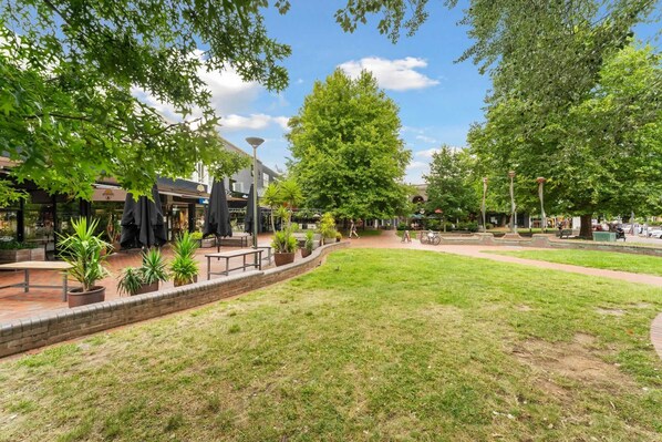 An outdoor area with a paved walkway, seating areas, and potted plants.