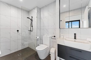 Une salle de bain moderne équipée d’une douche, de toilettes et d’un meuble-lavabo.